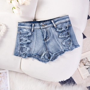 Dettaglio di pantaloncini di jeans blu con orlo sfrangiato e trama strappata alla moda