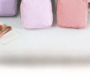 Détail de trousses à maquillage en seersucker rayé avec fermetures éclair métalliques