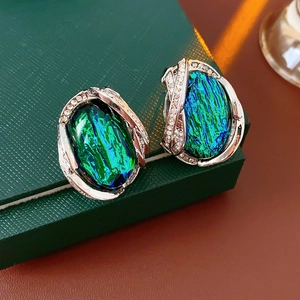 Macro view of vintage silver earrings with opal stones and crystals on a green jewelry box