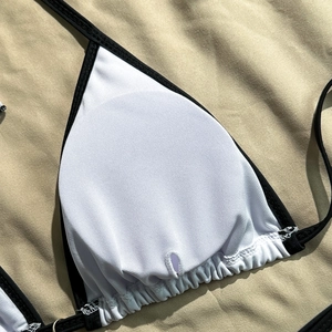 Detailed close-up of white bikini top with black trim and removable round pads