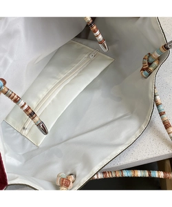 Detail view of the tote bag interior with beige lining, zipper pocket and rope handles