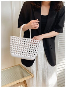 Detailed view of white hollow woven jelly basket bag held by a model in soft daylight