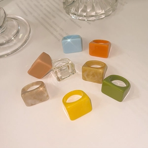 Vue rapprochée de plusieurs bagues carrées en résine colorée aux textures marbrées