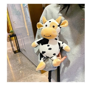 Detailed view of a soft plush cow-shaped crossbody bag with black and white spots