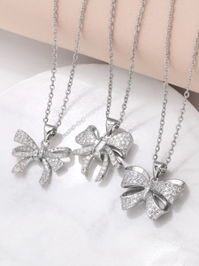 Detailed view of silver bow-knot pendants with shimmering zircon stones on marble