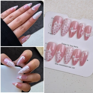 Detail of semi-handmade press-on nails with white floral relief and pearl accents