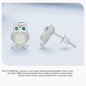 Detailed view of silver owl stud earrings with green stones and resin stones