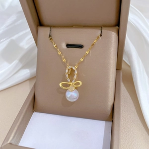 Titanium steel bow necklace with sparkling crystals and pearl in a beige jewelry box