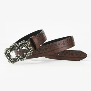 Detail of a brown leather belt with star patterns and a rhinestone heart buckle