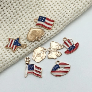 Detail of 7 golden alloy USA flag charms including star and heart shapes on beige fabric