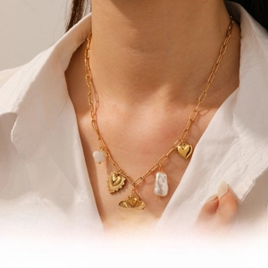 Détail d'un collier chaîne doré avec pendentifs fleur en perle et cœurs métalliques