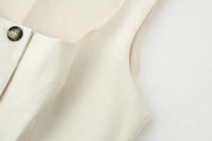 Close-up of beige square neck vest with brown button and cotton-linen fabric texture