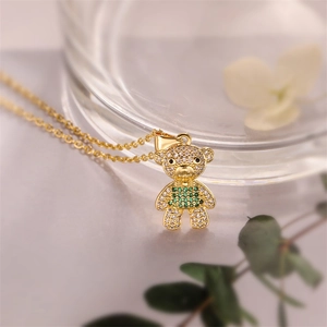 Macro view of gold-plated bear pendant necklace with green and clear zircon stones