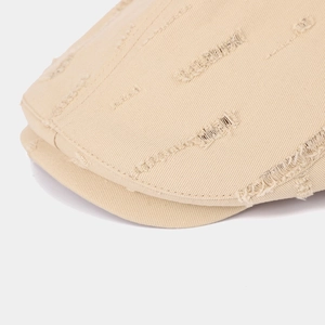 Close-up of distressed cotton fabric detail on khaki retro newsboy cap with frayed holes
