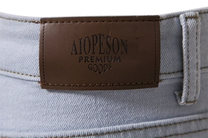 Detailed close-up of the premium brown leather patch on light blue denim jeans