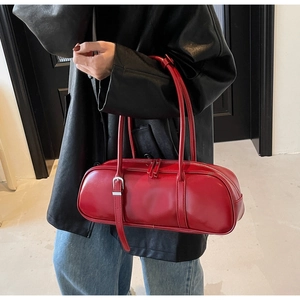 Close-up of red baguette shoulder bag in glossy faux leather with dual metal zippers