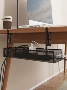 Close-up of black metal cable management tray clamped on desk with natural wood grain