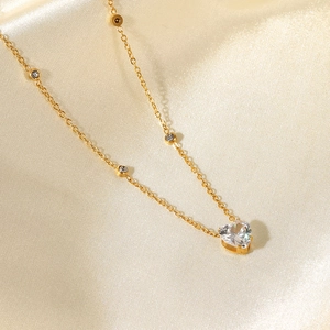 Detailed macro view of 18K gold plated necklace with white heart zircon on champagne silk