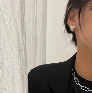 Minimalist silver heart stud earrings and paperclip chain necklace worn by a model