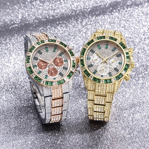 Close-up of luxury iced-out chronographs in gold and silver with green gem bezels