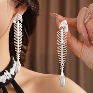 Detailed close-up of long silver fishbone earrings with sparkling zircons and pearls