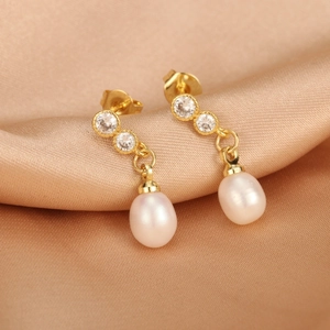 Detailed view of 18K gold plated pearl earrings with zircon inlay on silk background
