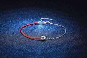 Macro view of S925 silver Moissanite bracelet with red braided cord and polished silver chain