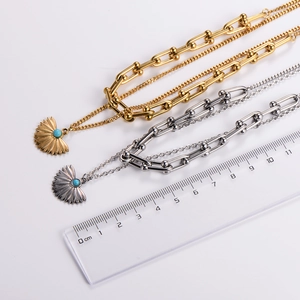 Close-up of gold and silver fan pendant necklaces with turquoise bead and gauge links