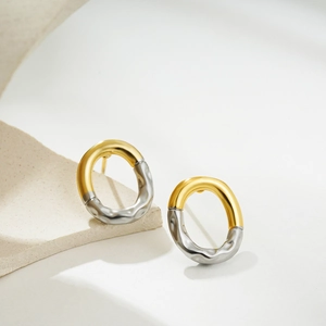 Detail of two-tone oval earrings with gold smooth finish and silver hammered texture