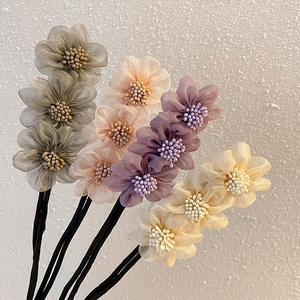 Dettaglio di quattro accessori per chignon a fiori in rete con perle in vari colori