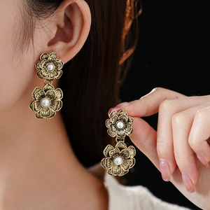 Detailed close-up of vintage gold floral earrings with pearls worn by a model