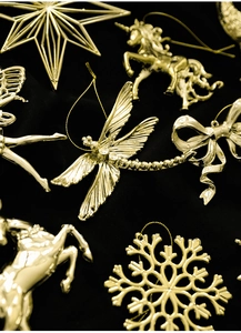 Close-up of golden Christmas tree ornaments like snowflakes and reindeer on black velvet