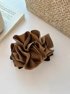 Détail d'un chouchou en satin marron en forme de fleur plissée avec élastique robuste