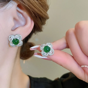 Detailed close-up of emerald flower stud earrings featuring silver petals and micro diamonds