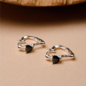 Macro shot of 925 sterling silver hoop earrings with black heart stones and lava texture