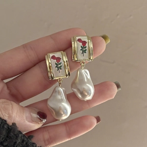 Macro detail of vintage rose pattern earrings with irregular baroque pearl drops