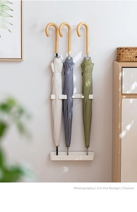 Detail of wall-mounted beige umbrella stand with drip tray for long umbrellas