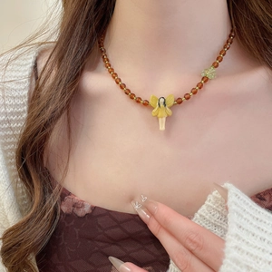 Detailed close-up of a fairy pendant necklace with amber beads and green leaf accents