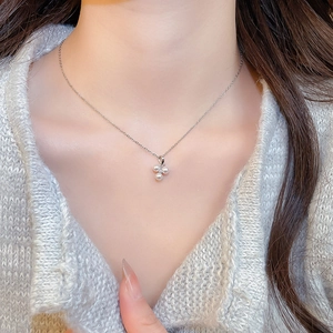 Close-up of stainless steel necklace featuring a triple pearl clover pendant on a model