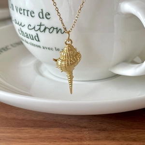 Minimalist 925 silver golden seashell pendant necklace on wood and ceramic background