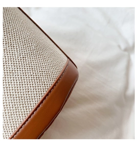 Close-up of woven canvas texture and brown leather stitching on minimalist bucket bag
