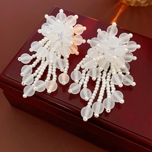Dettaglio orecchini bianchi con perline smerigliate e nappe pendenti eleganti