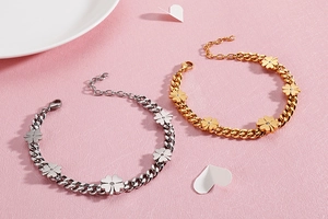Detail of gold and silver thick chain clover bracelets on a pink textured background