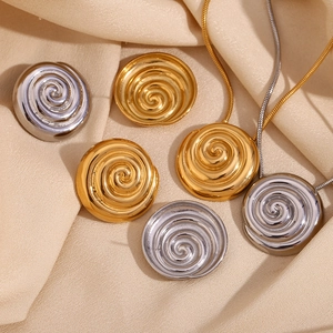 Detailed shot of gold and silver spiral earrings and necklaces on silk fabric
