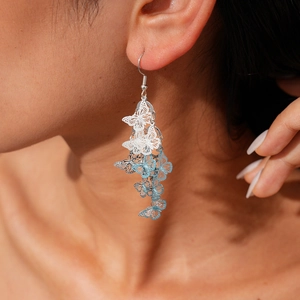 Detail of silver long tassel earrings with blue gradient butterfly pendants on model