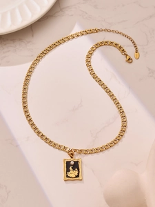 Detailed macro of gold vintage frame necklace with black oil drop and pearl relief