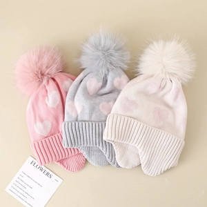 Detailed knit texture and heart pattern on girls winter earmuff hats with pom poms