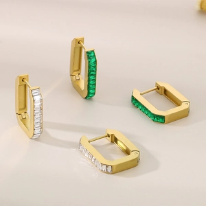 Detail of gold geometric earrings with emerald and white rectangular zircon stones