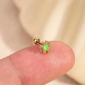 Piercing hélix fleur dorée avec opale verte et zircons présenté sur un doigt