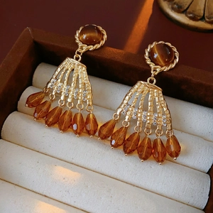 Close-up of vintage gold earrings with brown tiger eye stones and amber crystal drops
